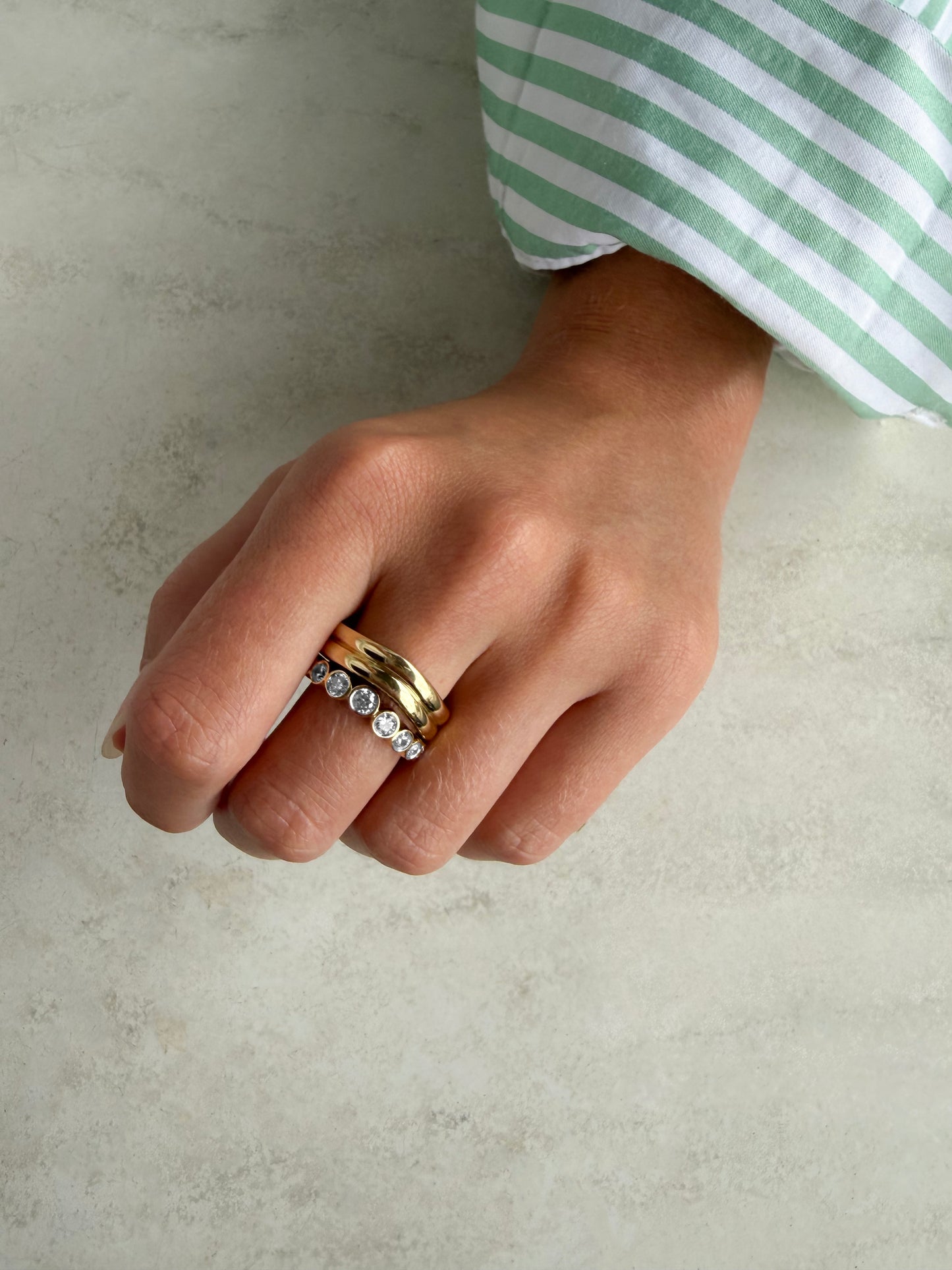 Side view of the AVA ring showing round lab-grown diamonds bezel-set in graduating sizes along a curved band