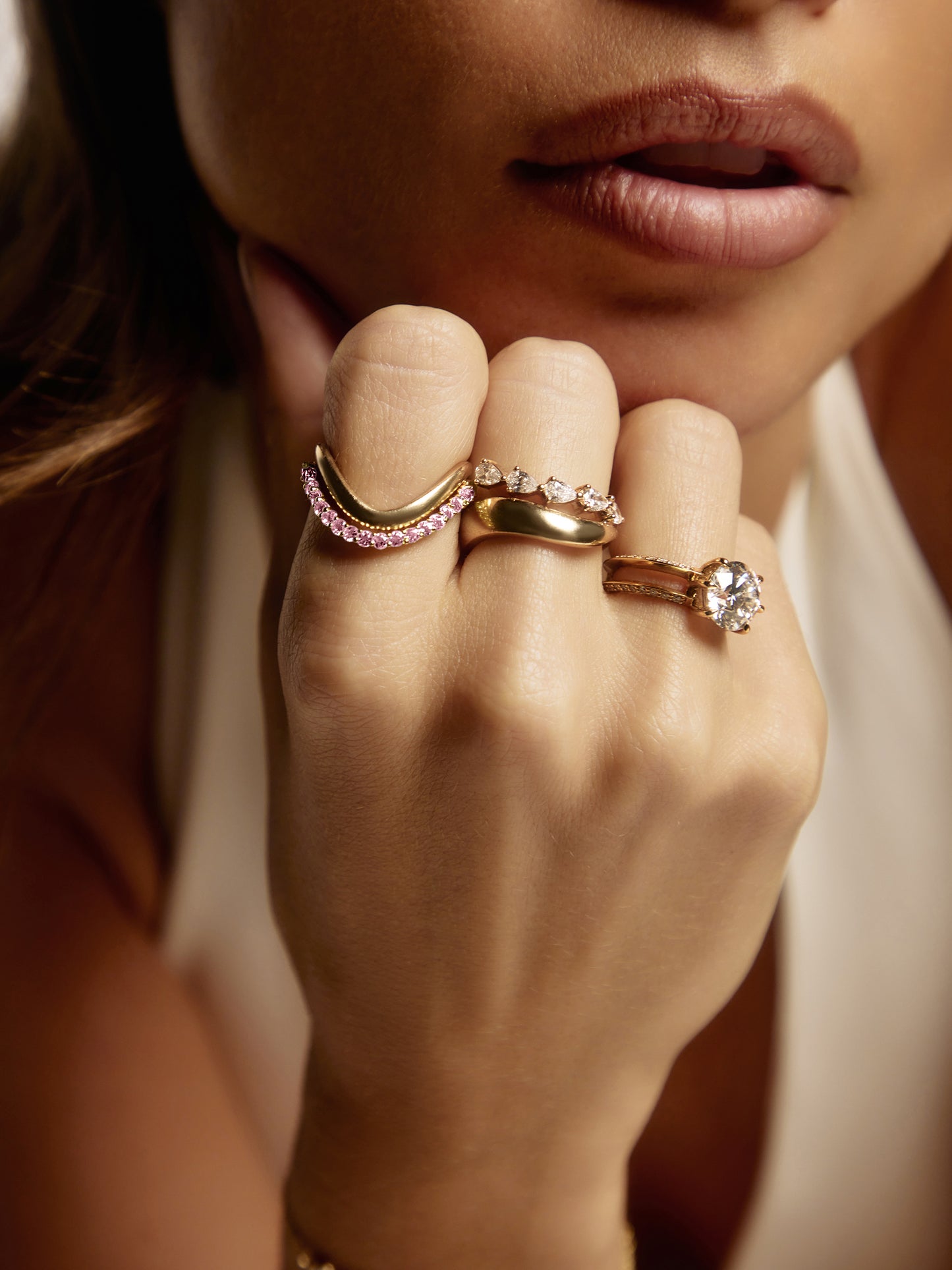 Side view of the SIA pink sapphire ring, a pink gemstone ring showing round pink sapphire pavé-set across a sculpted yellow gold curve