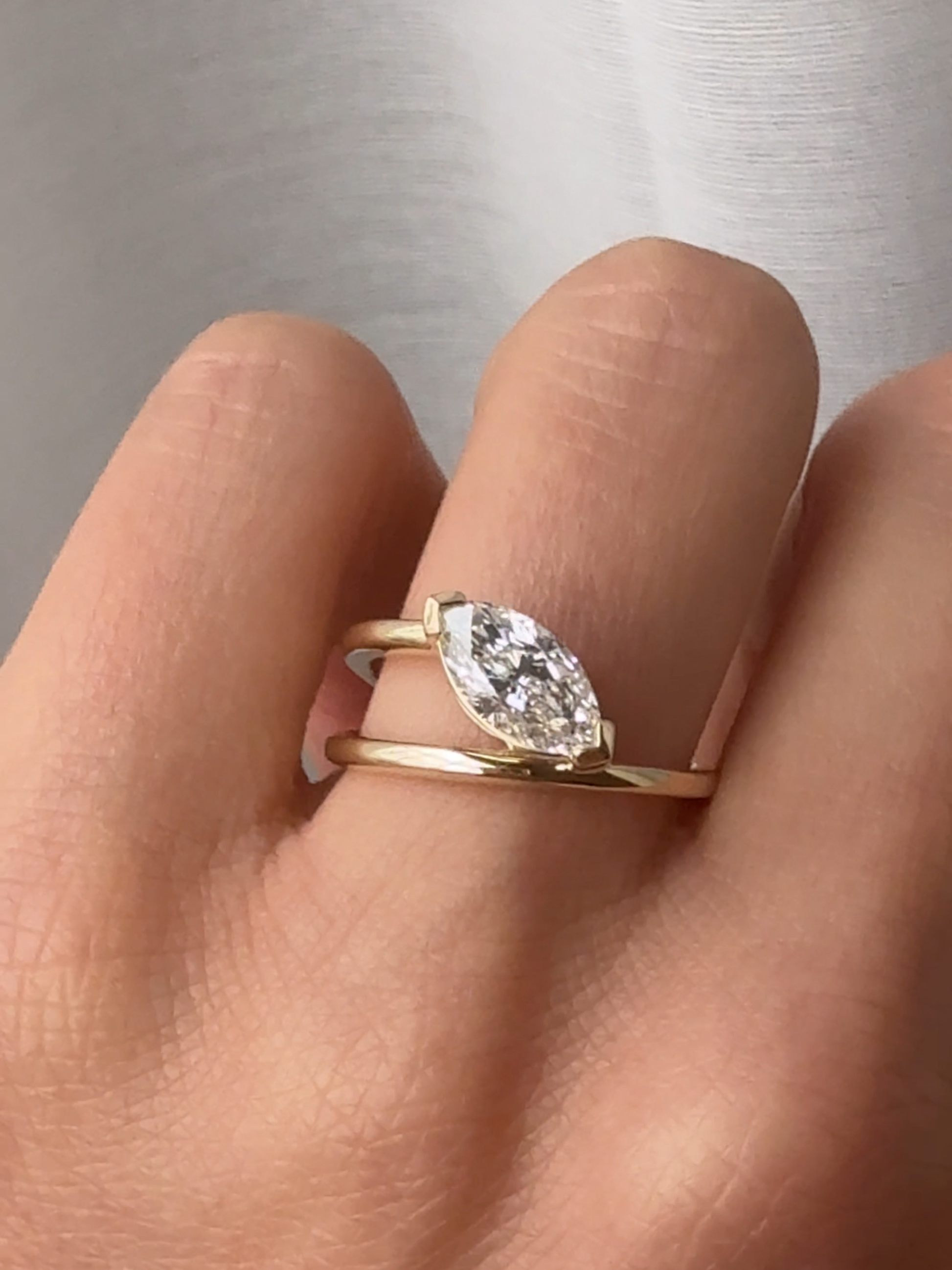 marquise pear diamond ring with a diamond on a finger against a neutral background