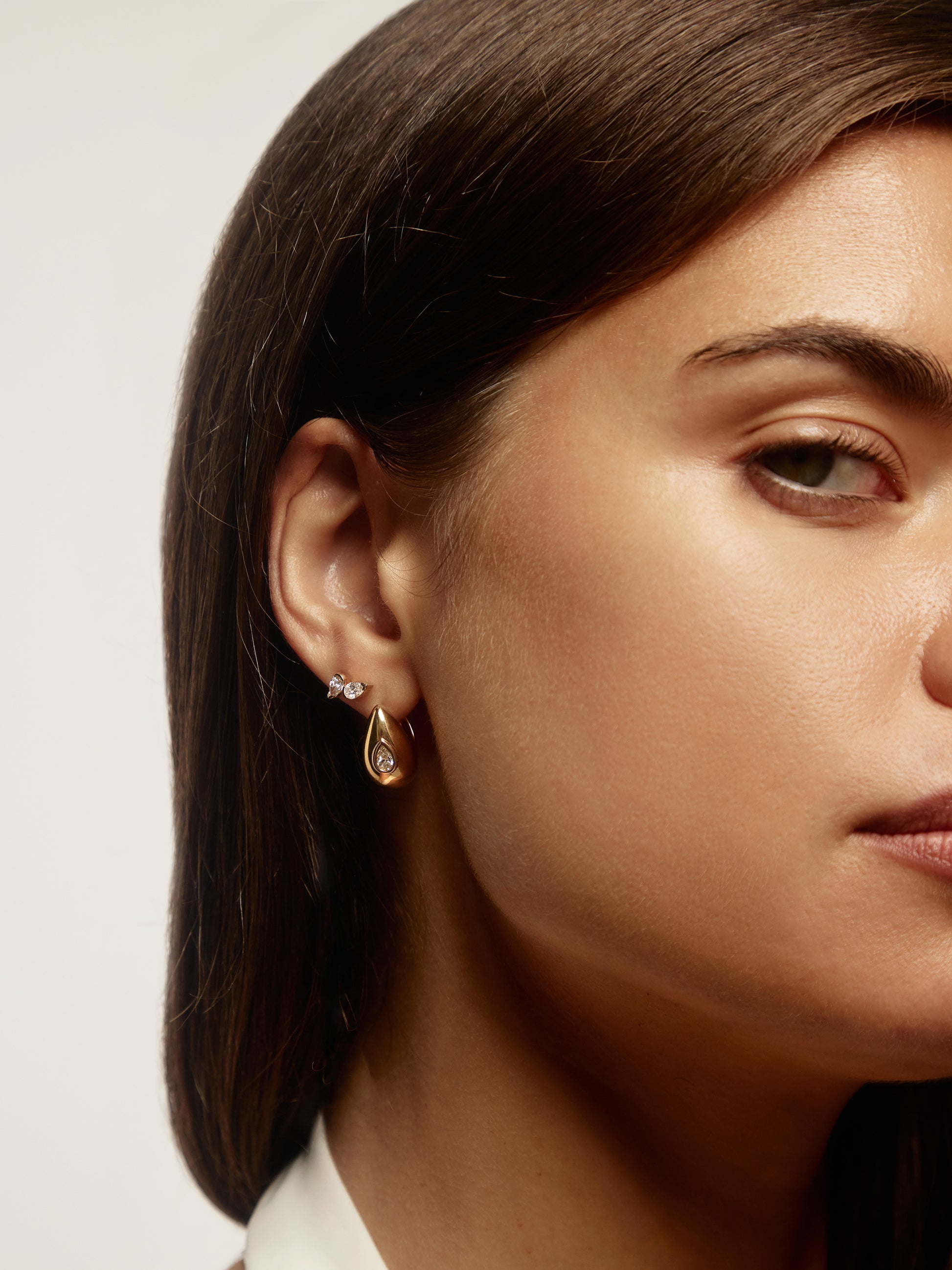 Side view of the ARI earring showing the sculptural drop silhouette with a bezel-set pear-cut diamond on the face