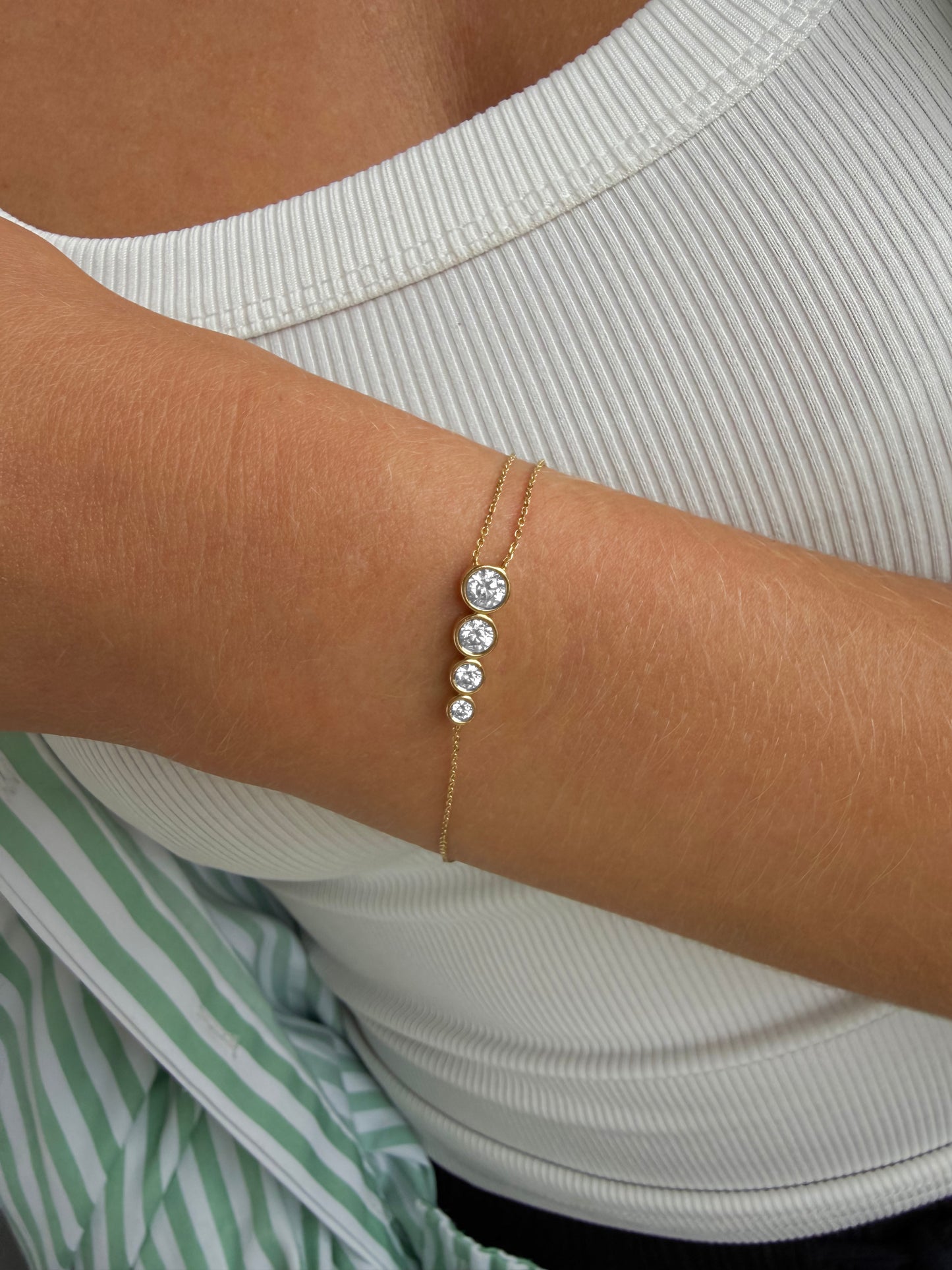 Side view of the AYLA bracelet showing four bezel-set diamonds graduating along the asymmetric 14ct yellow gold chain