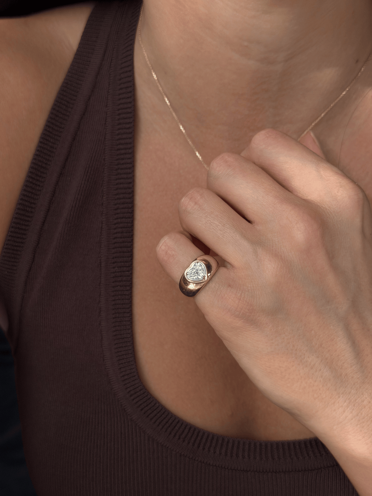 Side view of the DINA signet ring showing a heart-cut lab-grown diamond in a mixed-metal double bezel on a domed gold band