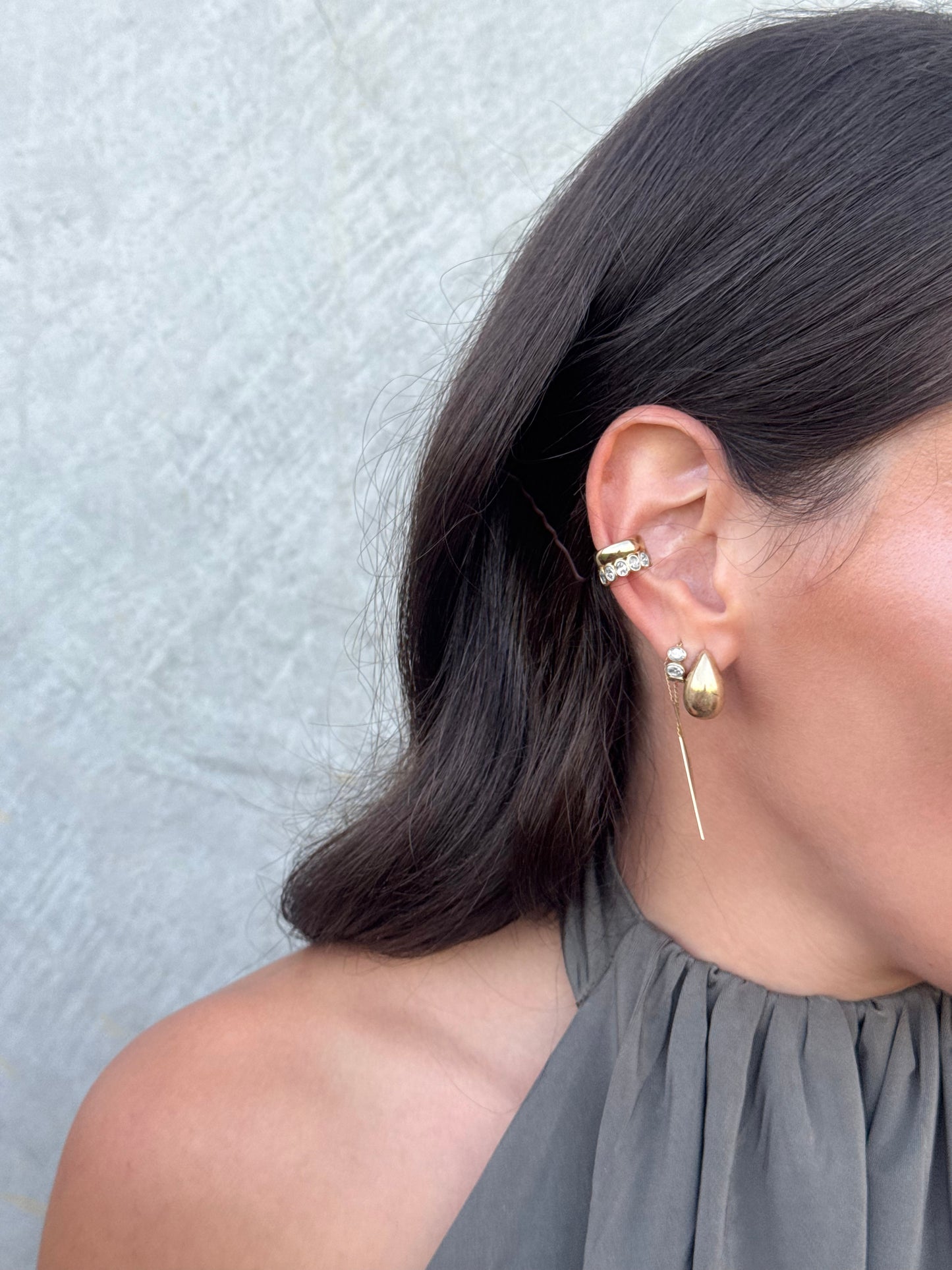Side view of the EZRA cuff showing a curved gold band bezel-set with oval diamonds, a sculptural ear cuff worn without a piercing