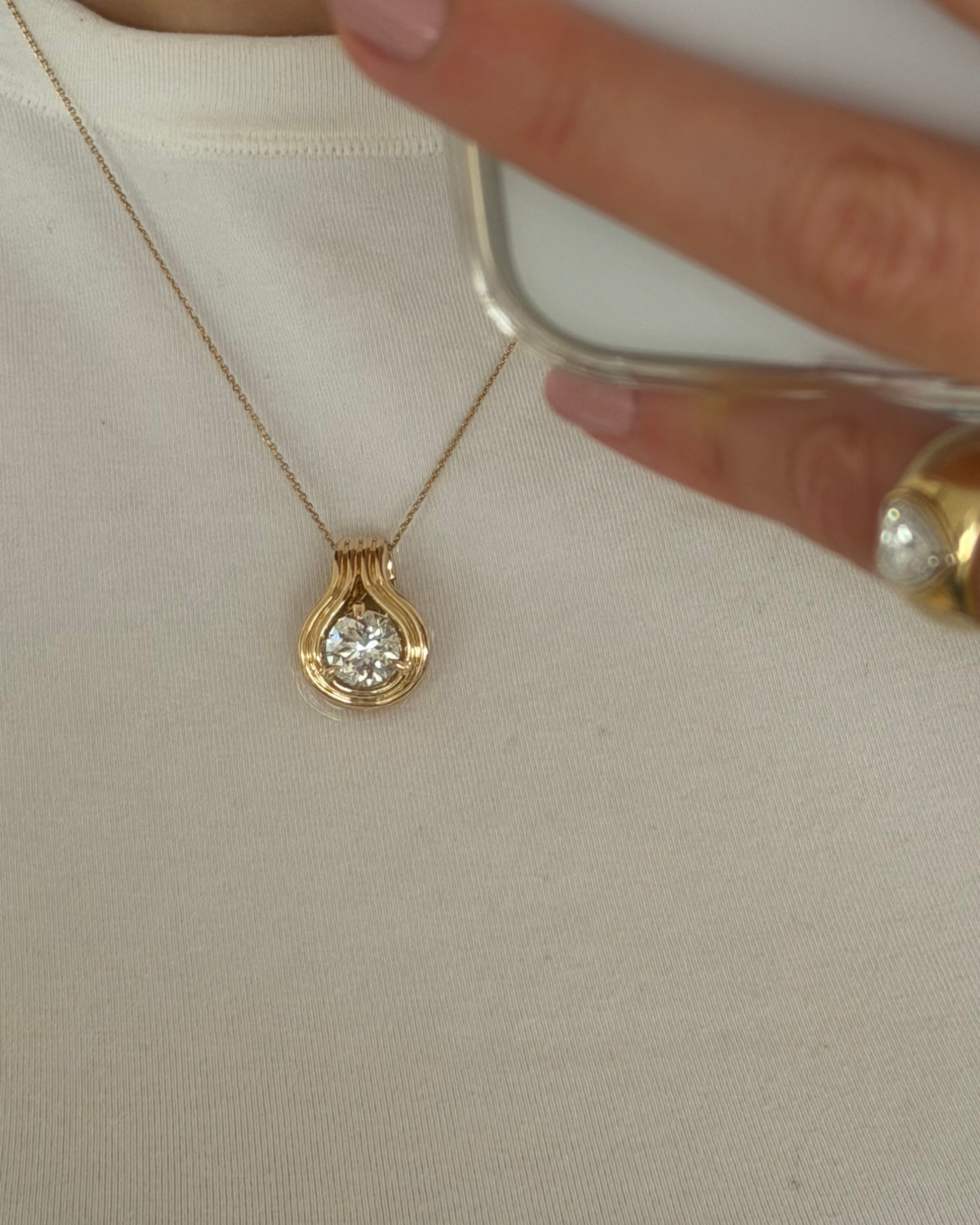 Side view of the NOA pendant showing the round brilliant diamond claw-set in a sculptural double band of 9ct yellow gold