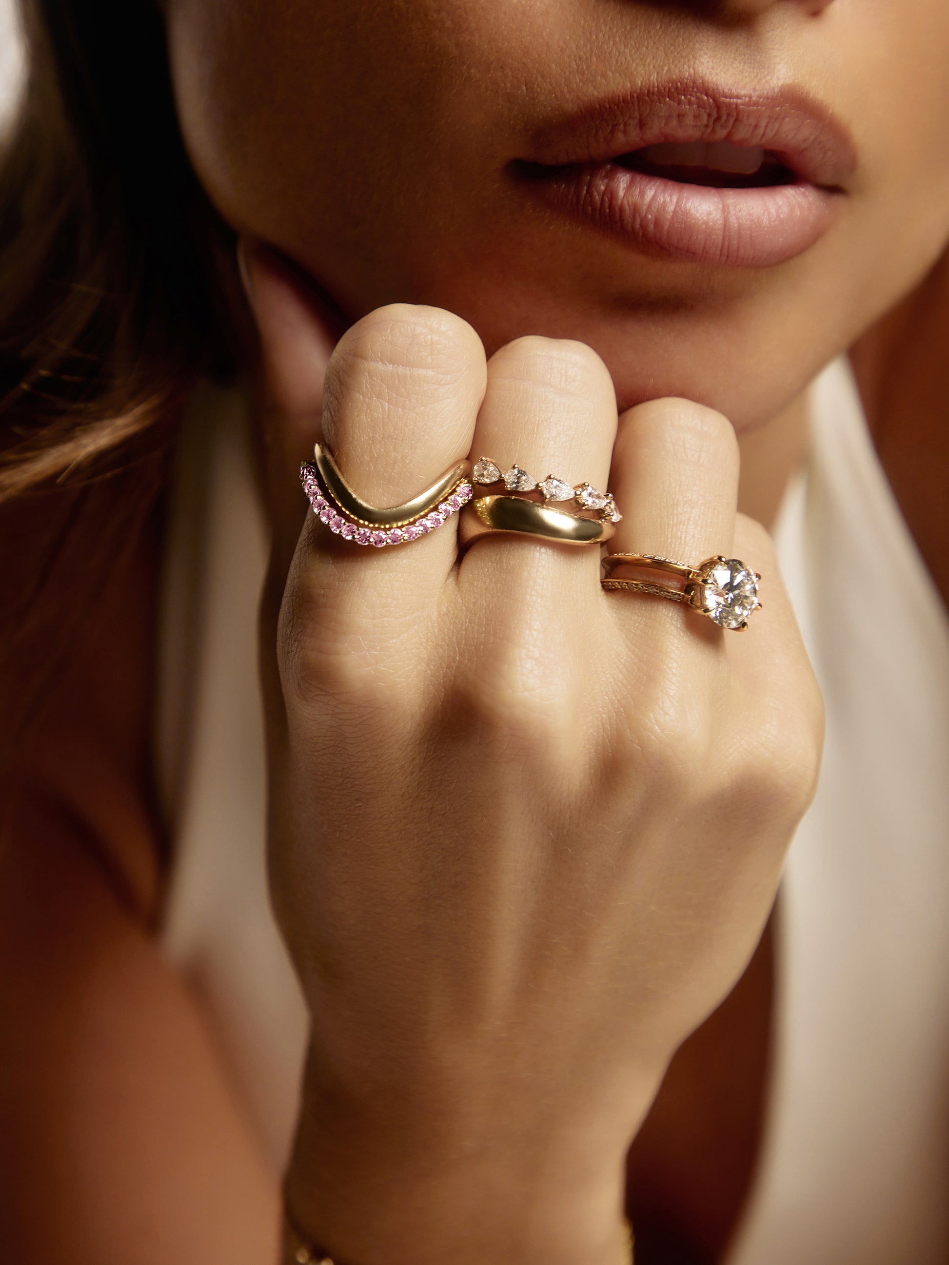 Side view of the SIA pink sapphire ring, a pink gemstone ring showing round pink sapphire pavé-set across a sculpted yellow gold curve