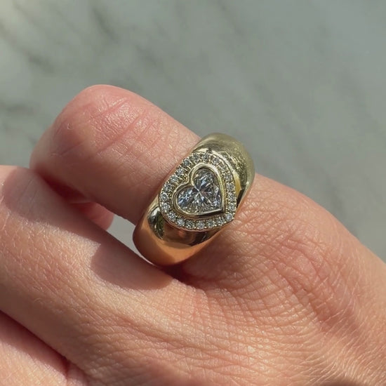 A video of Dina Halo gold heart signet in   a finger with white background